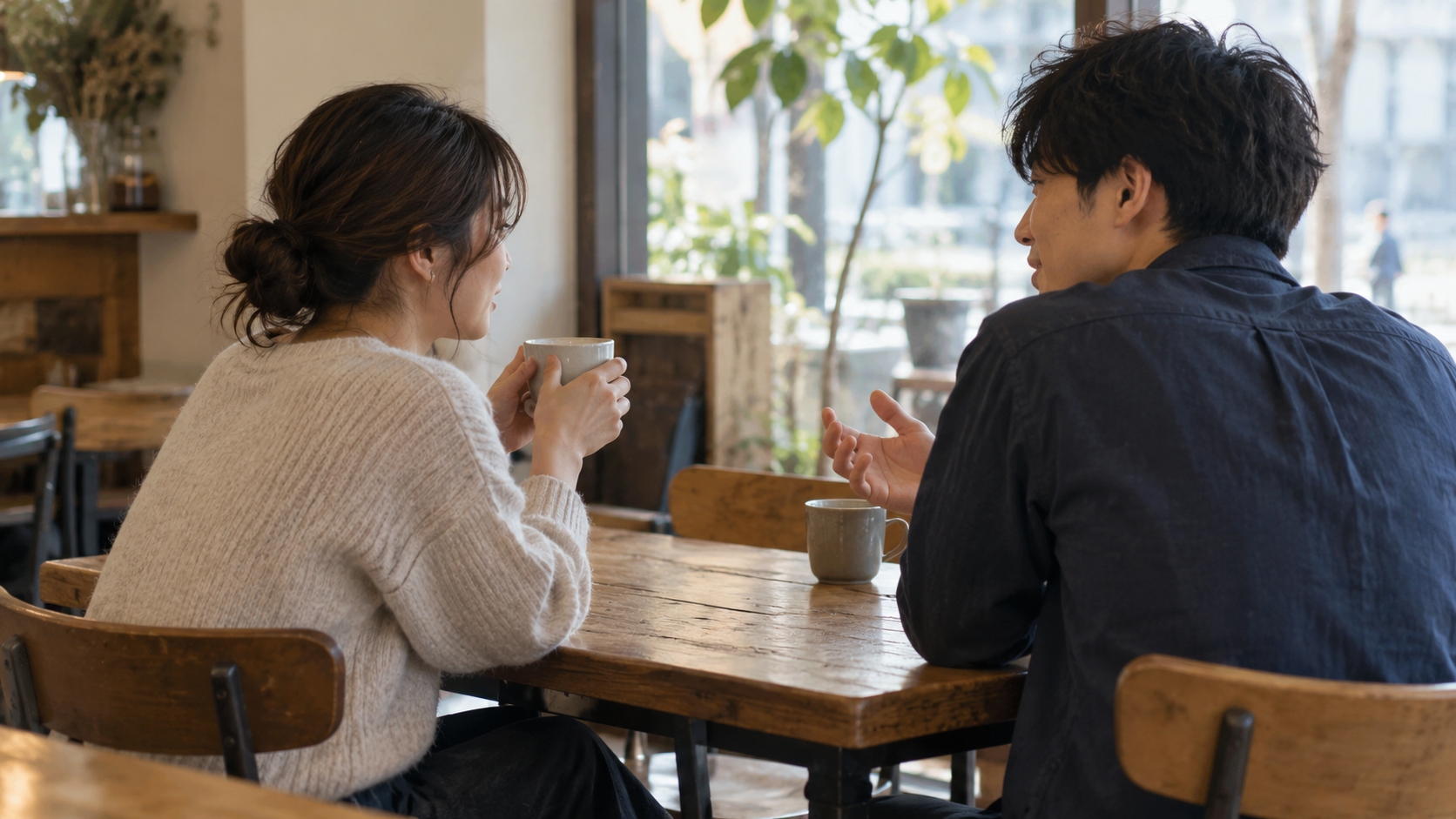 昼のカフェで向かい合って話す男女